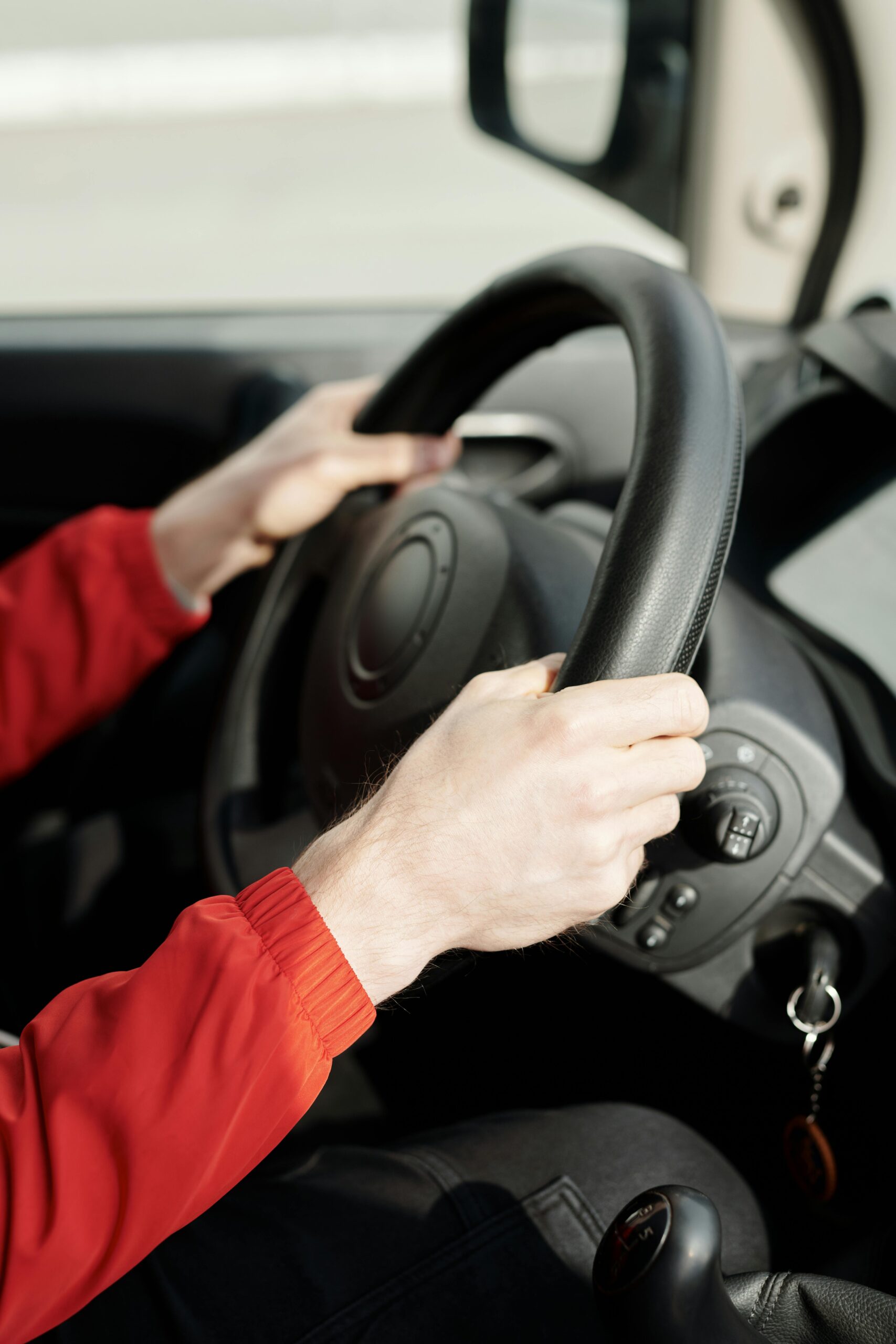 A person's hands gripping the steering wheel inside a vehicle, emphasizing safe driving.